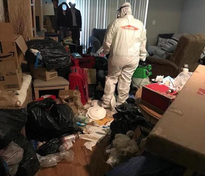 SERVPRO employee standing in a room filled with trash.