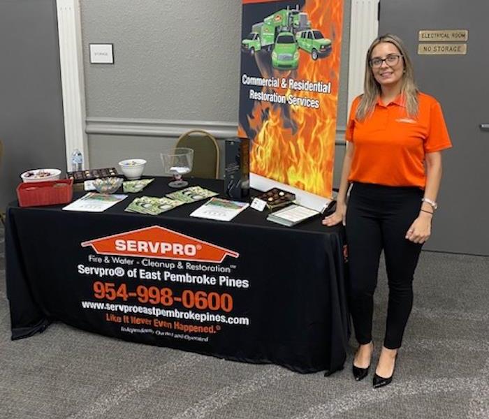 A female SERVPRO employee standing in front of a table. 