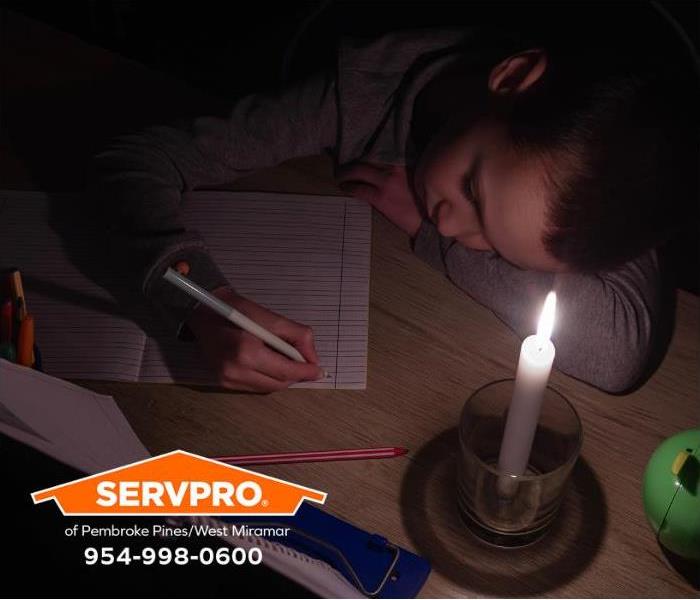 A student studies by candlelight during a power outage.