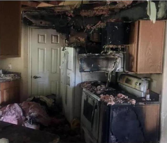 A kitchen covered in soot and smoke damage after a fire