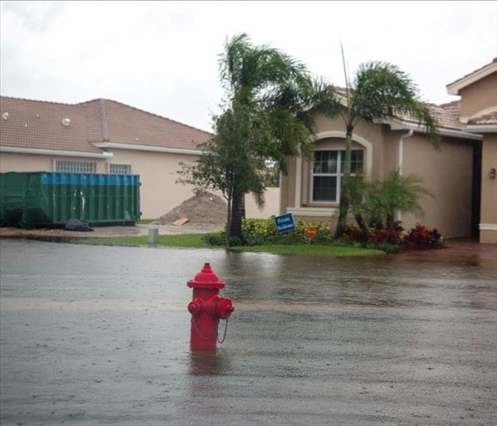 Two houses in a neighborhood surrounded by water from a storm. 